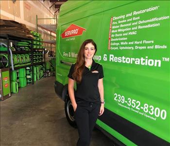 female employee in all black standing beside green van